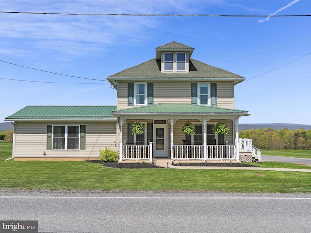 american foursquare style home with covered porch, a front lawn, and metal roof
