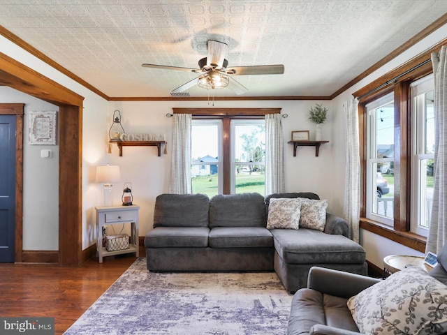 living area featuring an ornate ceiling, a ceiling fan, baseboards, and wood finished floors
