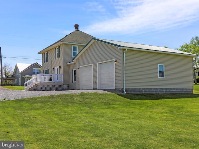 back of property with an attached garage, a yard, and a deck
