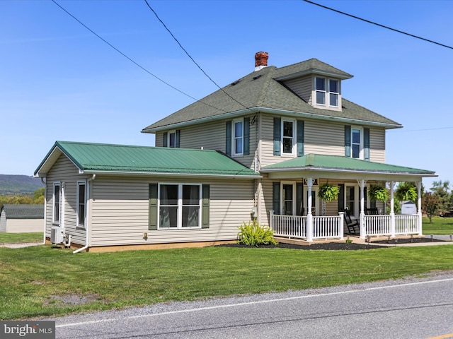 view of front of house with covered porch, a chimney, and a front lawn