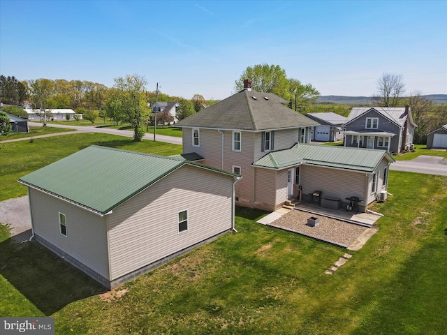 back of property featuring a patio, a yard, and metal roof
