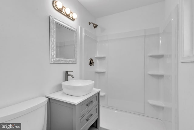 bathroom with toilet, a shower, and vanity