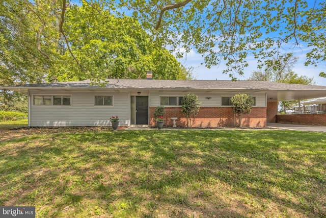 ranch-style home featuring brick siding, a front yard, a carport, and a chimney
