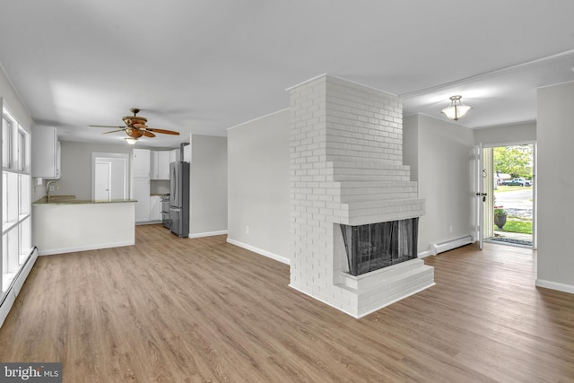 unfurnished living room featuring baseboard heating, a ceiling fan, light wood finished floors, and a fireplace