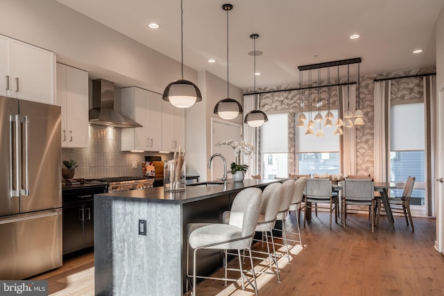 2001 Richmond St Unit 23B, Philadelphia, PA 19125 - kitchen with dark countertops, high end refrigerator, a sink, wall chimney exhaust hood, and an island with sink