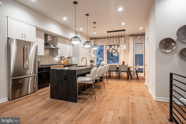 2001 Richmond St Unit 23B, Philadelphia, PA 19125 - kitchen with wall chimney range hood, dark countertops, high quality fridge, light wood finished floors, and a breakfast bar