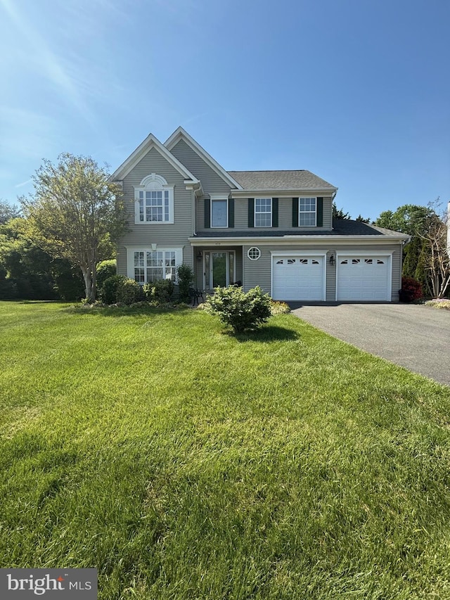 traditional home featuring an attached garage, driveway, and a front lawn