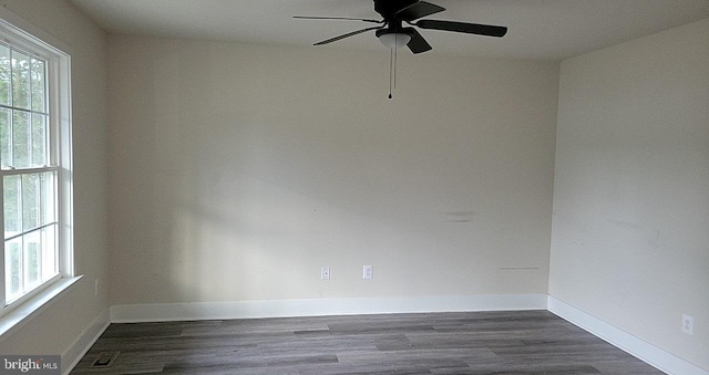empty room with baseboards, ceiling fan, dark wood-style flooring, and visible vents