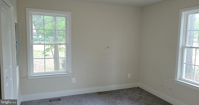 carpeted empty room with baseboards, a healthy amount of sunlight, and visible vents