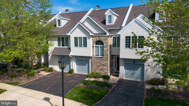 bi-level home with an attached garage, driveway, and stone siding