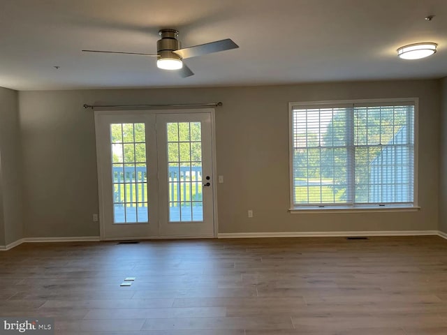 doorway with baseboards, ceiling fan, wood finished floors, and a wealth of natural light