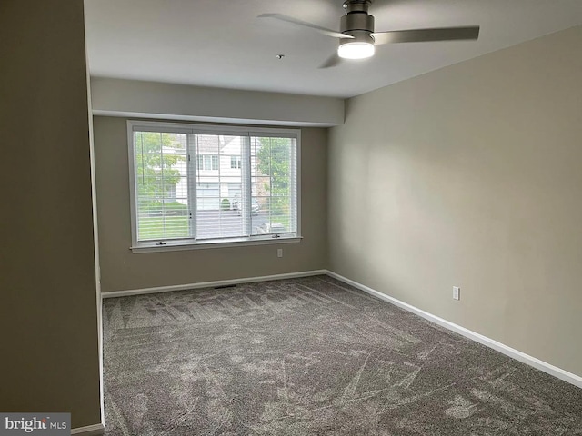 carpeted spare room with baseboards and a ceiling fan