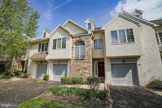 view of front of home with a garage, aphalt driveway, and stucco siding
