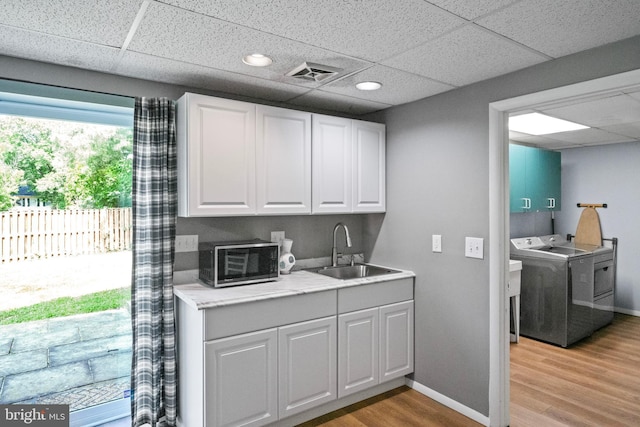 202 Trail Ct, Sterling, VA 20164 - kitchen featuring washer / clothes dryer, a sink, a drop ceiling, stainless steel microwave, and light wood-style flooring
