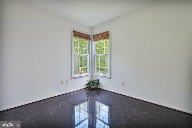 unfurnished room featuring granite tiled floors and baseboards