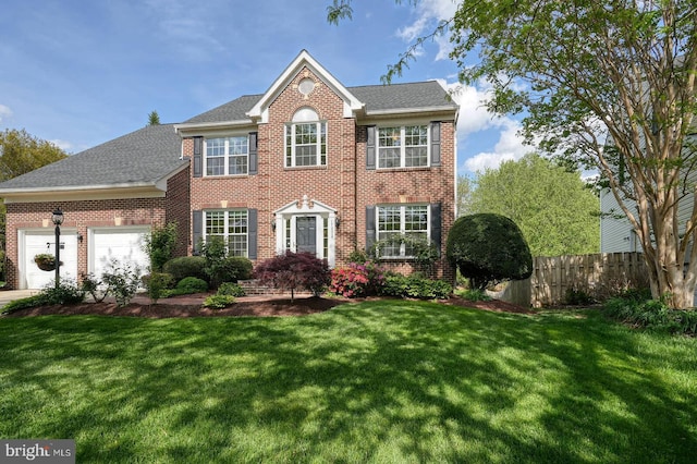 colonial home with brick siding, an attached garage, and roof with shingles