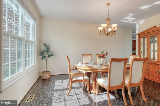 dining room featuring granite tiled floors, a chandelier, and baseboards