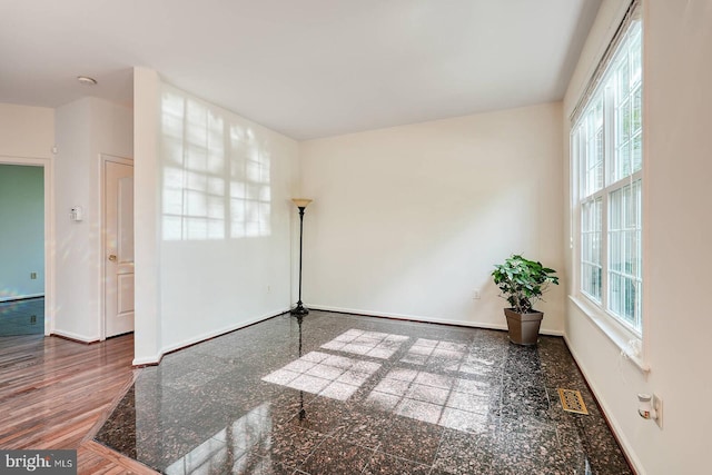 unfurnished room featuring baseboards, granite tiled floors, and a smoke detector