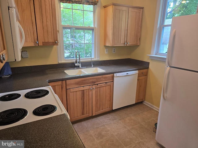 kitchen featuring white appliances, a sink, dark countertops, and baseboards