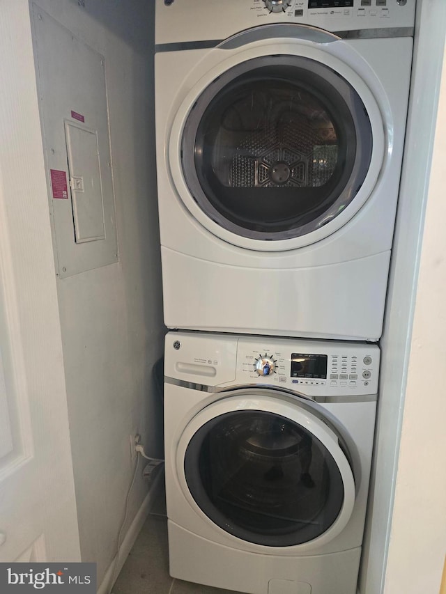 clothes washing area featuring stacked washing machine and dryer, electric panel, and tile patterned floors
