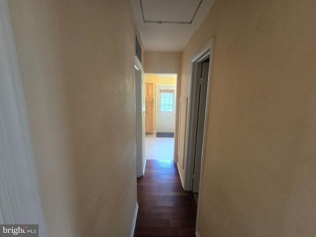 hallway featuring dark wood-style flooring and baseboards