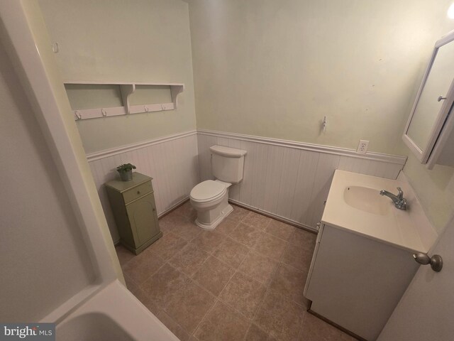 bathroom featuring a wainscoted wall, toilet, and vanity