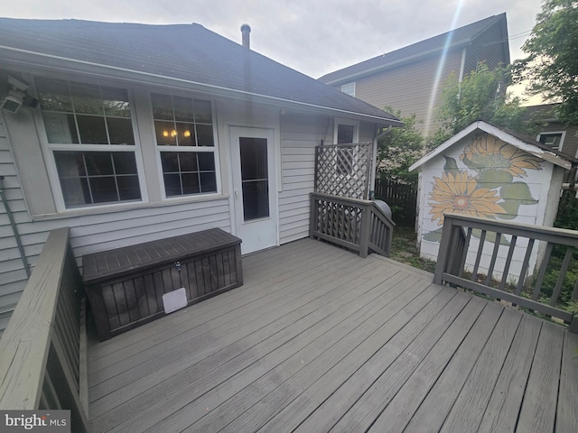 wooden terrace featuring an outdoor structure and a storage shed