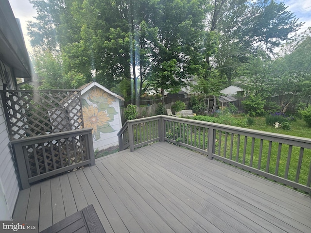 wooden terrace with a shed, an outbuilding, a fenced backyard, and view of scattered trees