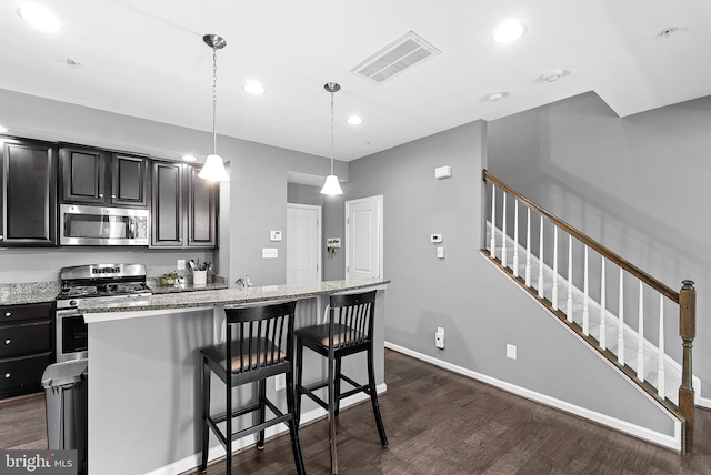 7471 Brunson Cir Unit 10A, Gainesville, VA 20155 - kitchen with stainless steel appliances, dark wood-style floors, a kitchen breakfast bar, light stone countertops, and a center island