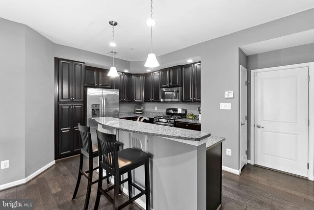 7471 Brunson Cir Unit 10A, Gainesville, VA 20155 - kitchen featuring stainless steel appliances, dark wood-type flooring, a breakfast bar area, decorative light fixtures, and light stone counters