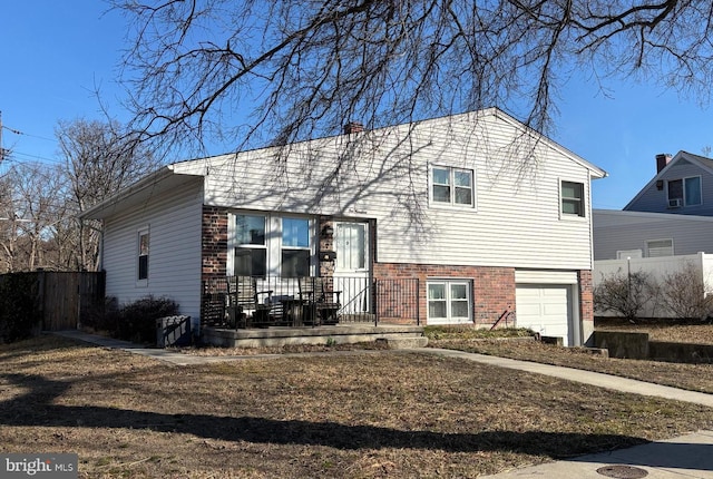 tri-level home featuring a garage, fence, and brick siding