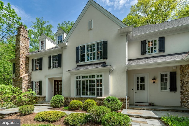 view of front of property with a shingled roof, stucco siding, a standing seam roof, and stone siding