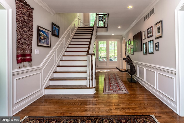 stairway featuring crown molding, visible vents, and a decorative wall