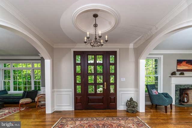 entrance foyer featuring wood finished floors, wainscoting, arched walkways, and a notable chandelier