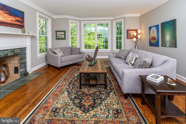 living room featuring ornamental molding, a brick fireplace, baseboards, and wood finished floors
