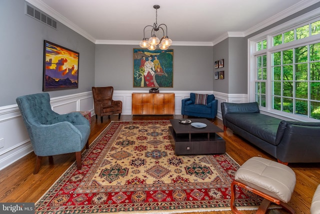 living room with a notable chandelier, crown molding, visible vents, and wood finished floors