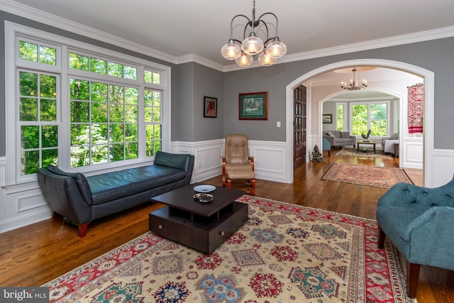 living area featuring an inviting chandelier, arched walkways, plenty of natural light, and wood finished floors