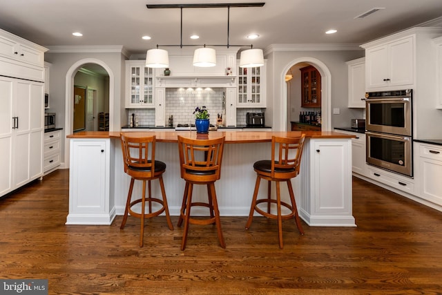 kitchen featuring ornamental molding, butcher block counters, a center island, and appliances with stainless steel finishes