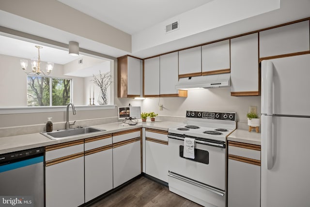 135 Woodlake Dr, Marlton, NJ 08053 - kitchen featuring white appliances, under cabinet range hood, a sink, light countertops, and dark wood-style flooring