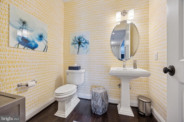 bathroom with hardwood / wood-style flooring, baseboards, and wallpapered walls