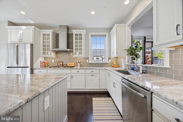 kitchen featuring a sink, wall chimney exhaust hood, white cabinets, and stainless steel appliances