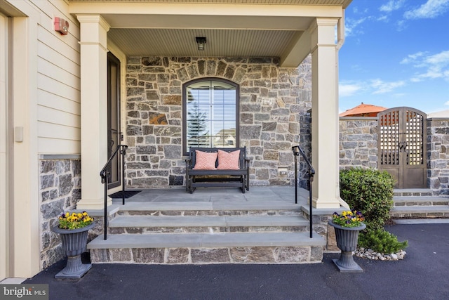 view of exterior entry with a porch and stone siding