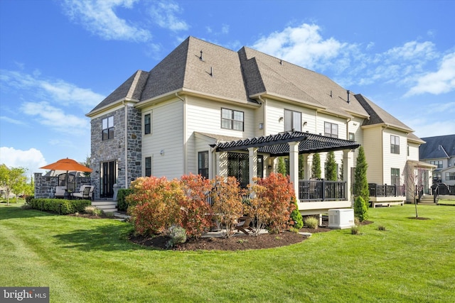 back of property featuring a lawn, ac unit, a wooden deck, a pergola, and a shingled roof