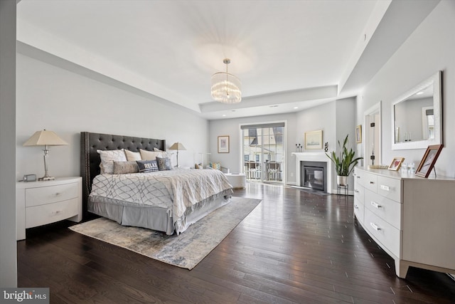 bedroom featuring a tray ceiling, a chandelier, and dark wood-type flooring