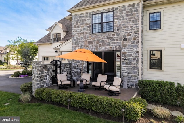 rear view of house featuring a shingled roof and stone siding