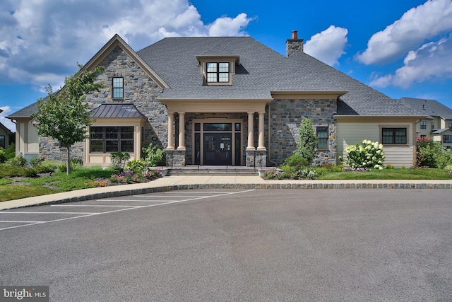 view of front of house featuring a chimney, uncovered parking, and stone siding