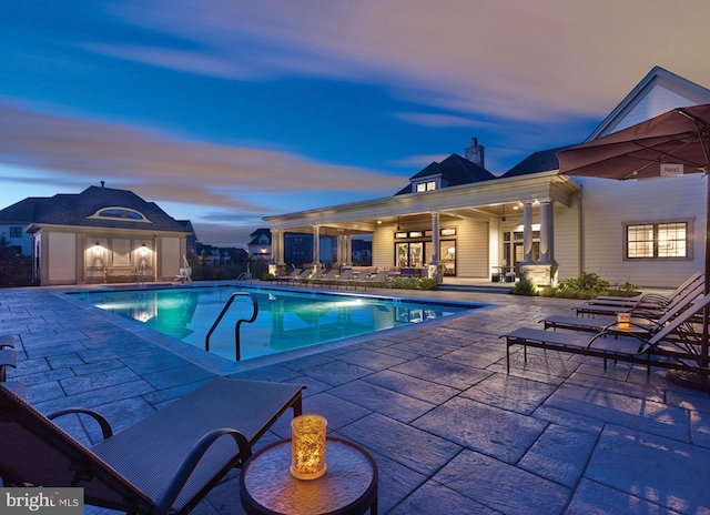 pool at dusk with a community pool and a patio area