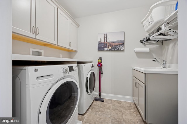 clothes washing area featuring cabinet space, separate washer and dryer, baseboards, and a sink