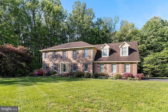 colonial inspired home with brick siding and a front lawn