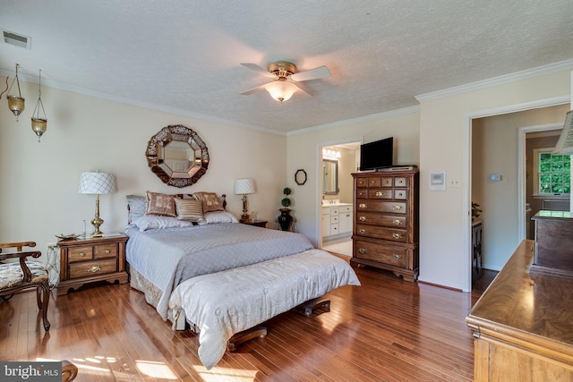 bedroom with a textured ceiling, visible vents, ornamental molding, and wood finished floors